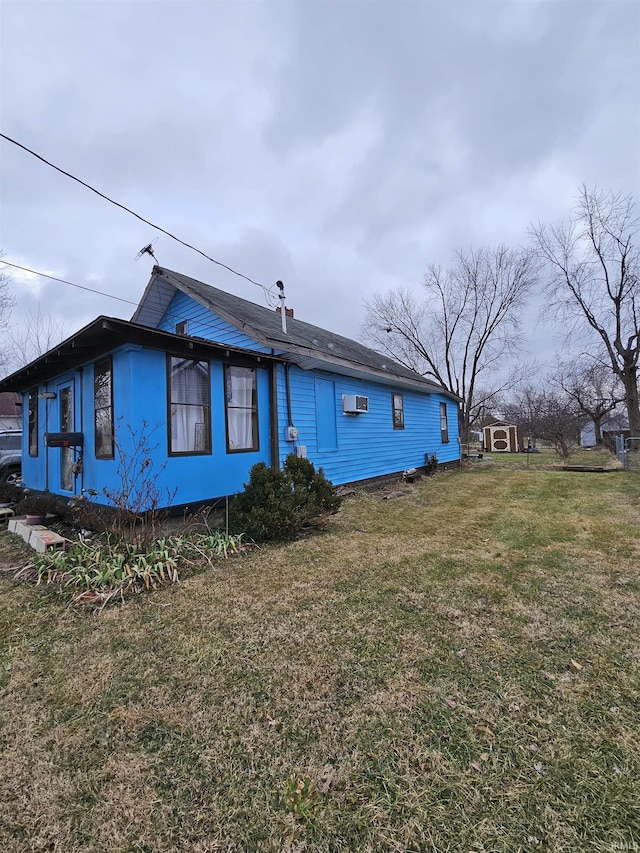 back of property with a wall unit AC and a yard