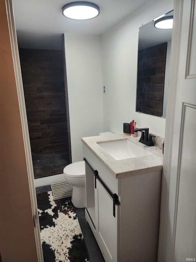 bathroom featuring a shower, toilet, and vanity