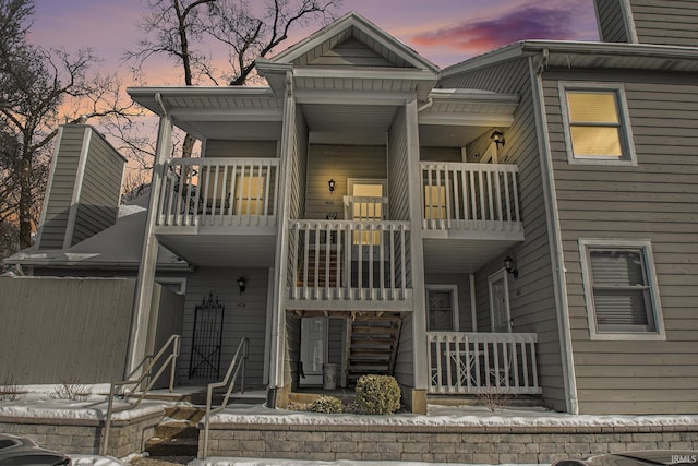 back house at dusk featuring a balcony