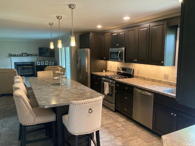 kitchen featuring stainless steel appliances, pendant lighting, crown molding, a center island, and a kitchen bar