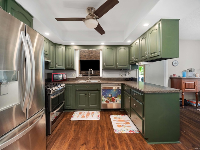 kitchen featuring green cabinets, a peninsula, appliances with stainless steel finishes, and dark countertops