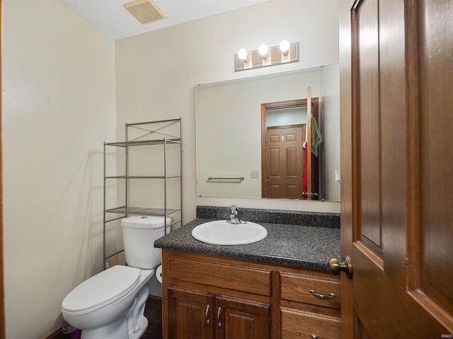 bathroom with visible vents, vanity, and toilet