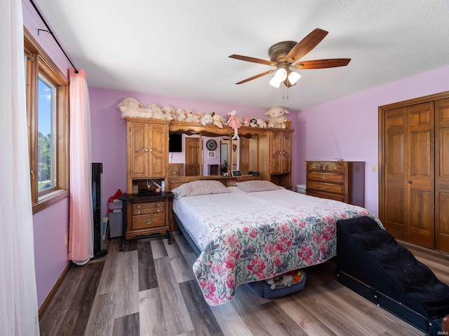 bedroom with baseboards, ceiling fan, wood finished floors, a textured ceiling, and a closet