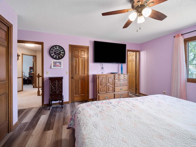 unfurnished bedroom with a textured ceiling, ceiling fan, dark wood-style flooring, and baseboards