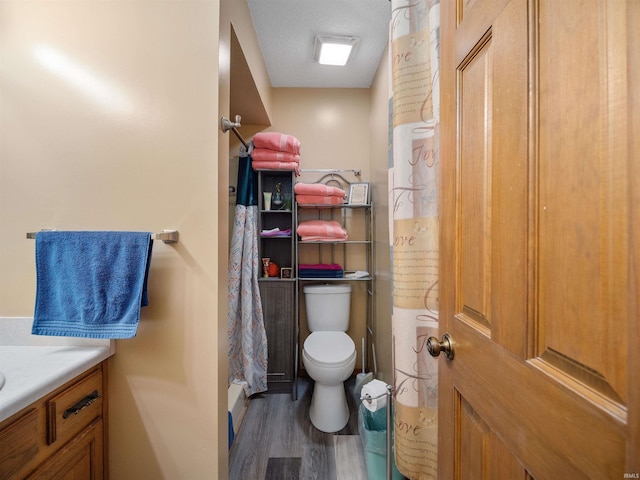 bathroom with curtained shower, vanity, toilet, and wood finished floors