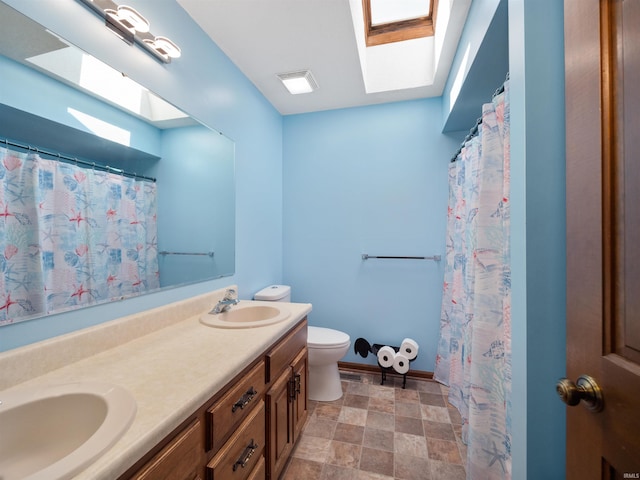 full bath featuring a skylight, a sink, toilet, and double vanity