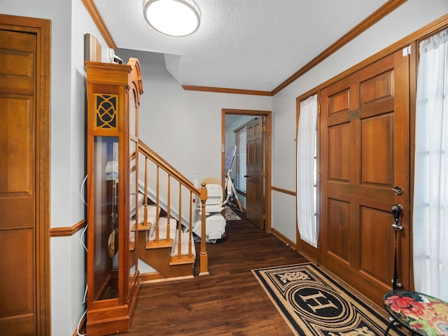 foyer entrance featuring a textured ceiling, dark wood-type flooring, stairway, and ornamental molding