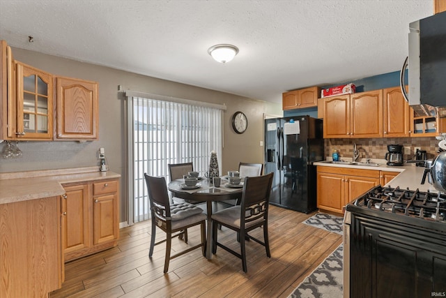 kitchen featuring light hardwood / wood-style flooring, sink, backsplash, a textured ceiling, and appliances with stainless steel finishes