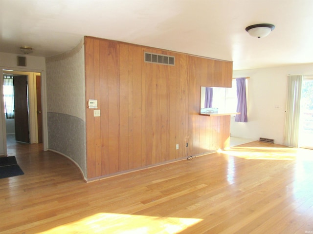 unfurnished room featuring light hardwood / wood-style floors and wood walls