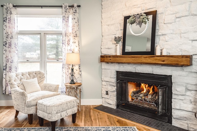 sitting room with a fireplace, baseboards, and wood finished floors