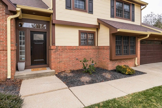 view of exterior entry with brick siding and a shingled roof