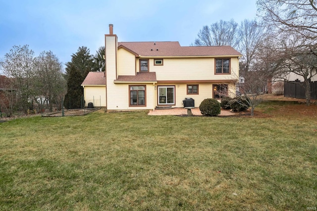 rear view of house with a chimney, a yard, and fence