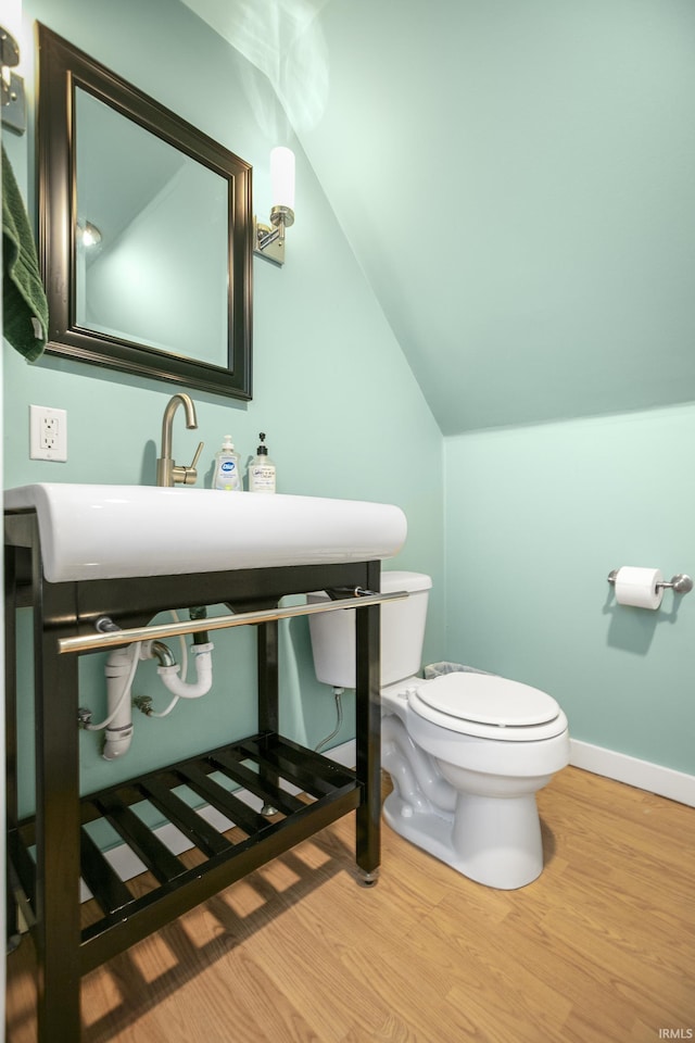 bathroom with hardwood / wood-style floors, toilet, and vaulted ceiling