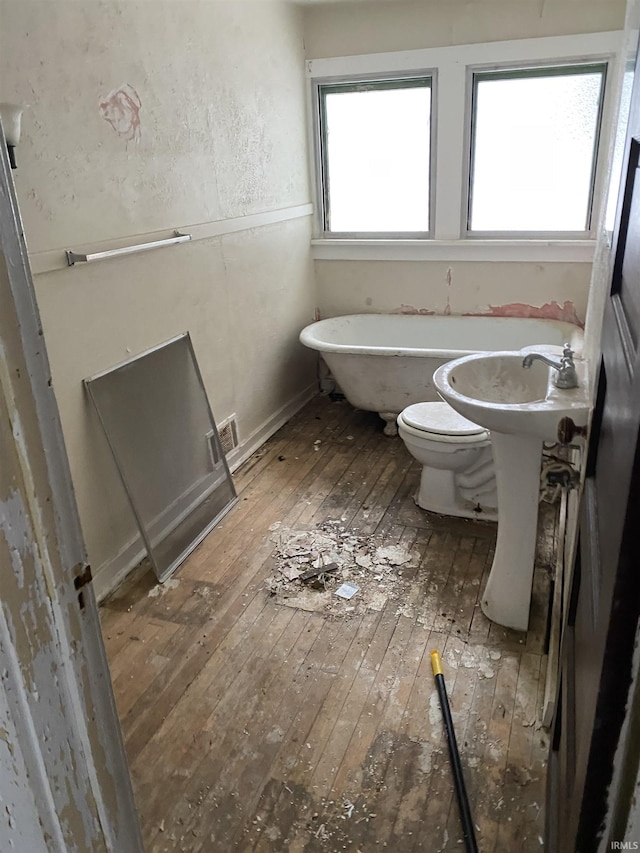 bathroom featuring a sink, wood finished floors, visible vents, a soaking tub, and toilet