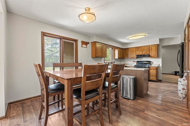 dining space featuring baseboards, wood finished floors, and a textured ceiling