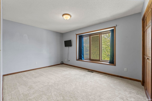 carpeted empty room featuring visible vents, baseboards, and a textured ceiling