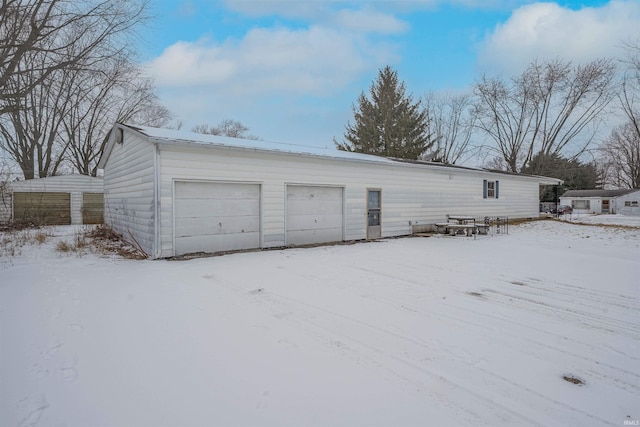 snow covered garage with a detached garage