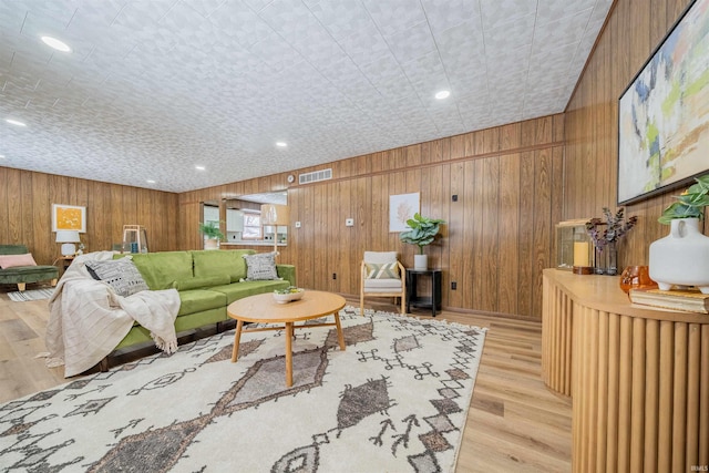 living room with visible vents, recessed lighting, light wood finished floors, and wood walls