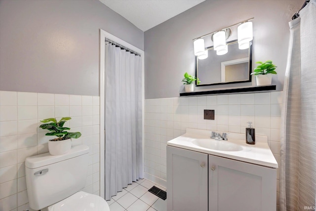 full bathroom with toilet, visible vents, vanity, tile walls, and tile patterned floors