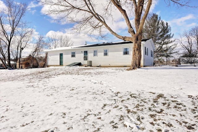 snow covered rear of property featuring a garage and central air condition unit