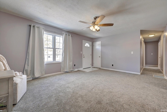 interior space featuring a ceiling fan, baseboards, a textured ceiling, and light colored carpet