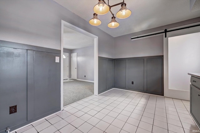 unfurnished dining area with light tile patterned floors, a barn door, a decorative wall, and light colored carpet