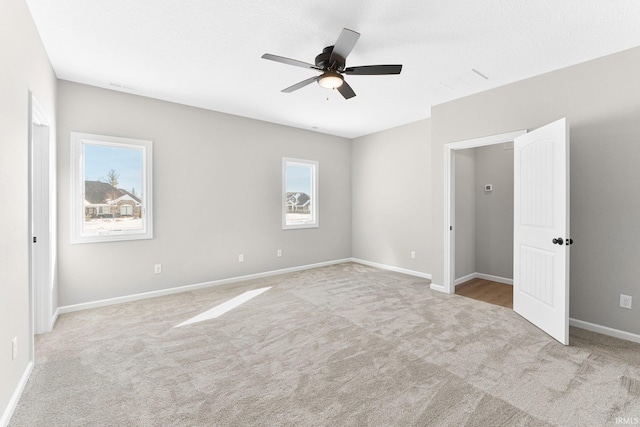 unfurnished bedroom featuring light carpet, baseboards, and a ceiling fan