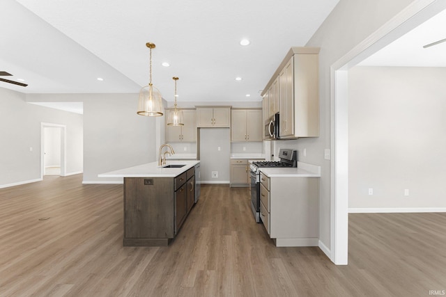 kitchen with a center island with sink, decorative light fixtures, stainless steel appliances, light countertops, and a sink