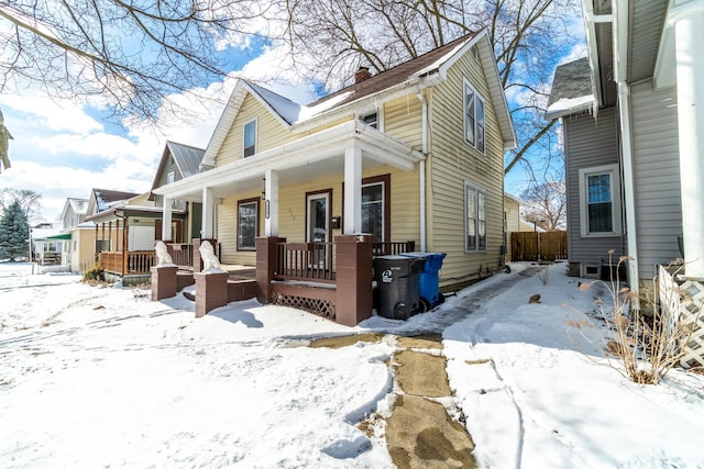 view of snow covered exterior featuring a porch and a chimney