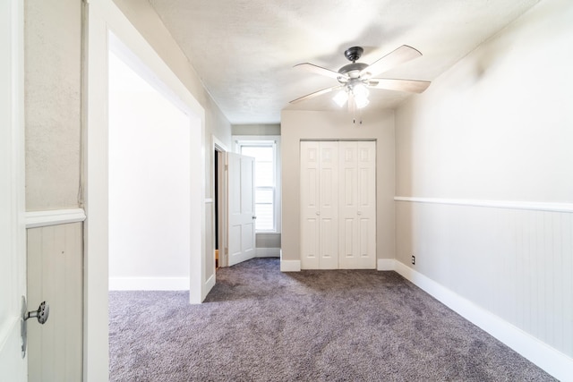 unfurnished bedroom featuring carpet, a closet, ceiling fan, and baseboards