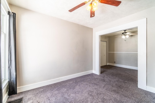 spare room featuring ceiling fan, carpet flooring, visible vents, baseboards, and wainscoting