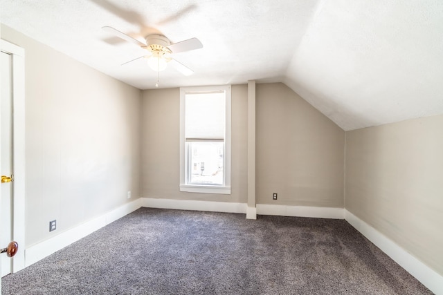 bonus room with dark carpet, vaulted ceiling, a textured ceiling, ceiling fan, and baseboards