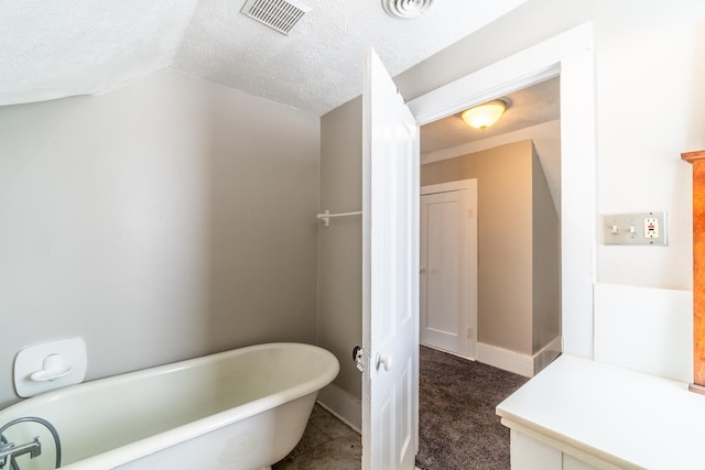 full bathroom with lofted ceiling, visible vents, a freestanding bath, a textured ceiling, and vanity