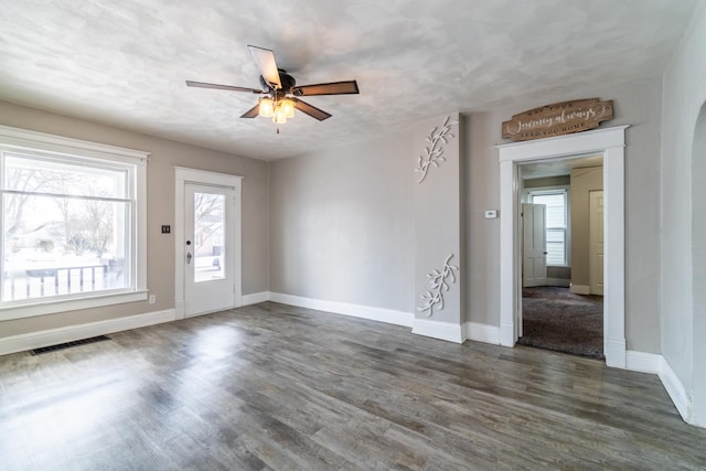 interior space with visible vents, dark wood-type flooring, a ceiling fan, a textured ceiling, and baseboards