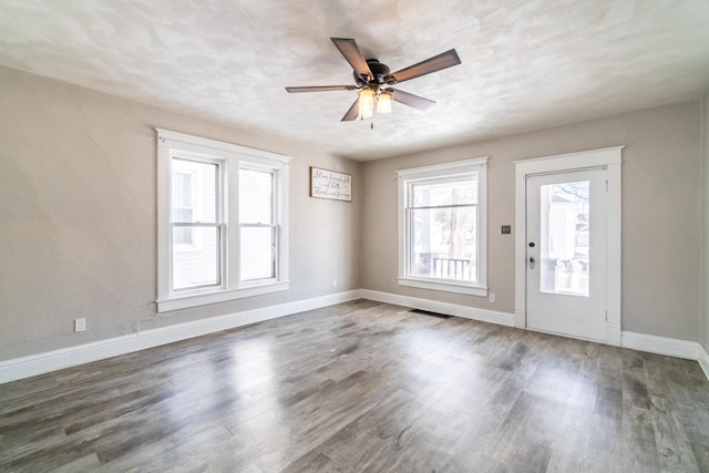 unfurnished room featuring ceiling fan, visible vents, baseboards, and dark wood-type flooring