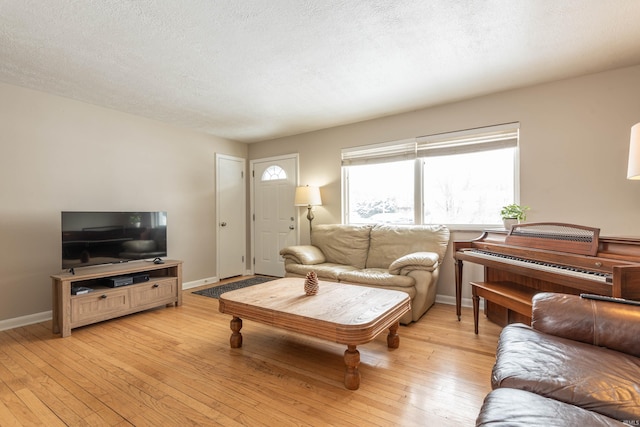 living area featuring light wood-style flooring, baseboards, and a textured ceiling