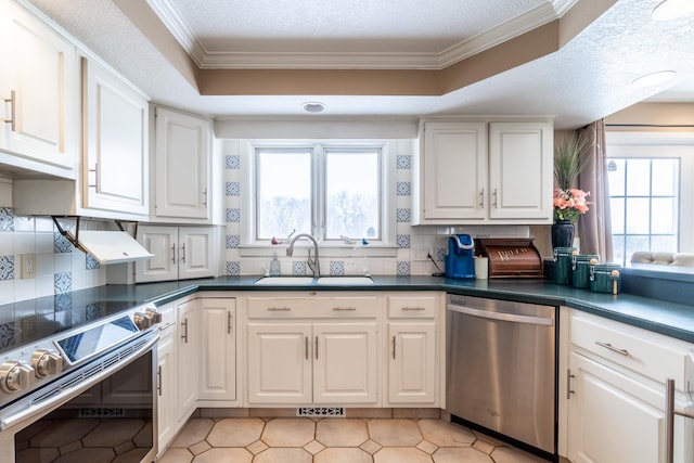 kitchen with dark countertops, appliances with stainless steel finishes, white cabinets, and a sink