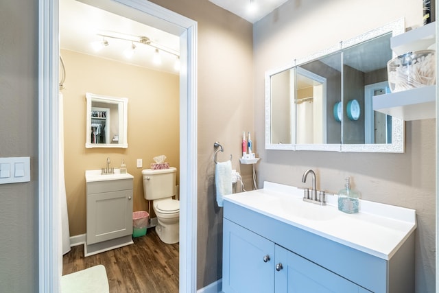 full bathroom with two vanities, a sink, toilet, and wood finished floors