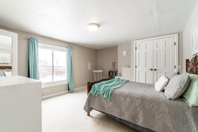 bedroom featuring baseboards, a closet, and light colored carpet