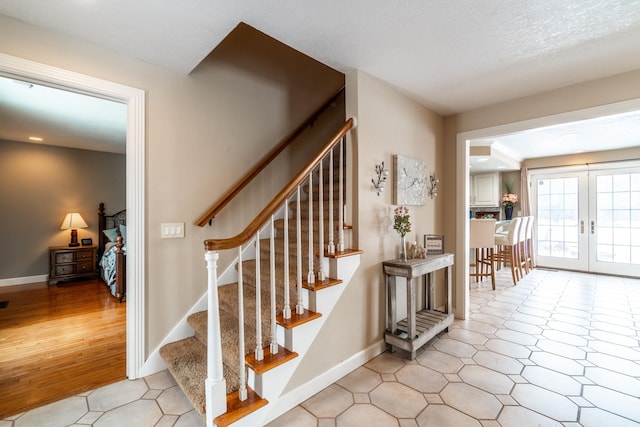 stairs with a textured ceiling, french doors, and baseboards