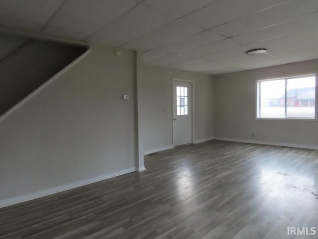 unfurnished room with baseboards, a drop ceiling, and dark wood-type flooring