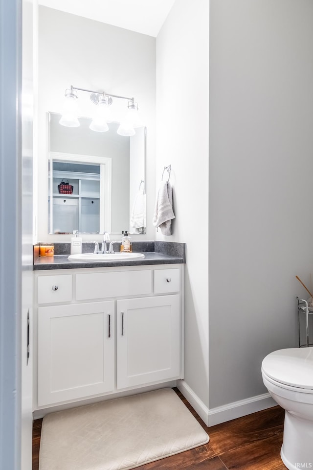 bathroom with toilet, baseboards, wood finished floors, and vanity