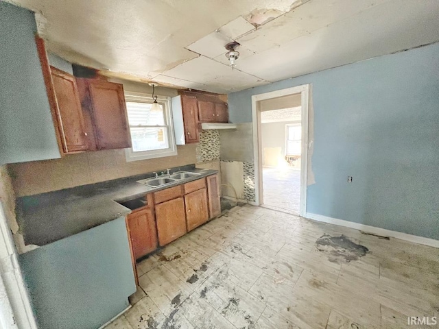 kitchen with dark countertops, baseboards, brown cabinetry, and a sink