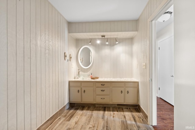 bathroom with rail lighting, wood finished floors, and vanity