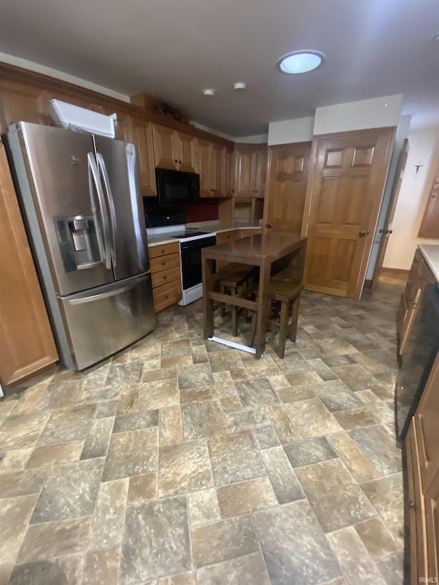 kitchen featuring white electric stove, black microwave, light countertops, stone finish floor, and stainless steel fridge