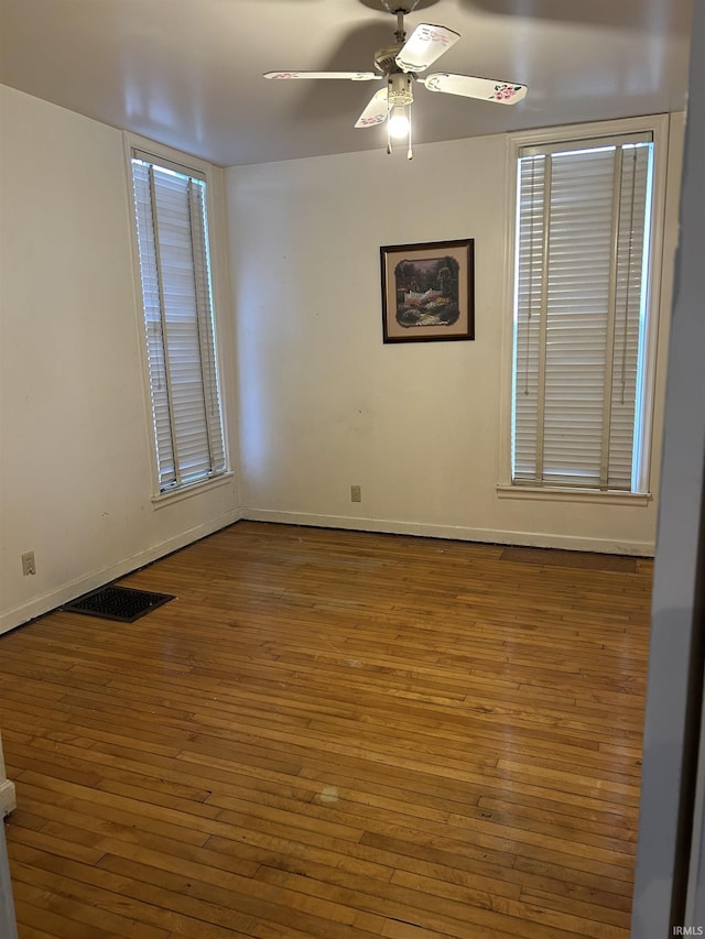 unfurnished room with visible vents, ceiling fan, baseboards, and wood finished floors