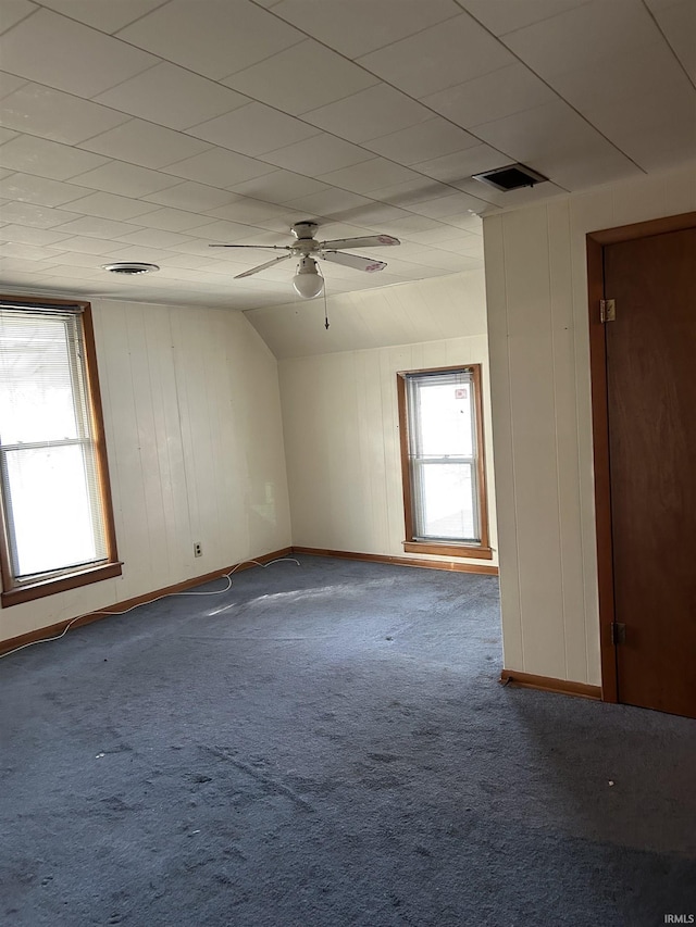 carpeted empty room with a ceiling fan, lofted ceiling, visible vents, and baseboards