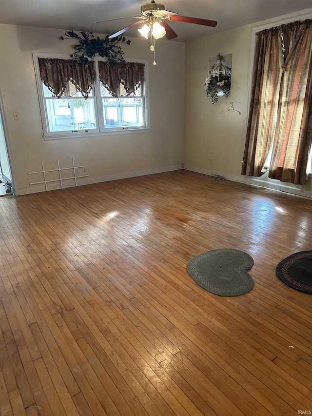 spare room featuring a ceiling fan, baseboards, and light wood finished floors