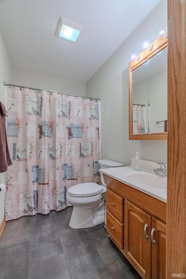 bathroom with vanity, toilet, and a textured ceiling