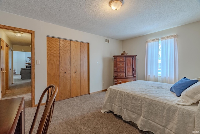 bedroom featuring light carpet, baseboards, visible vents, a textured ceiling, and a closet